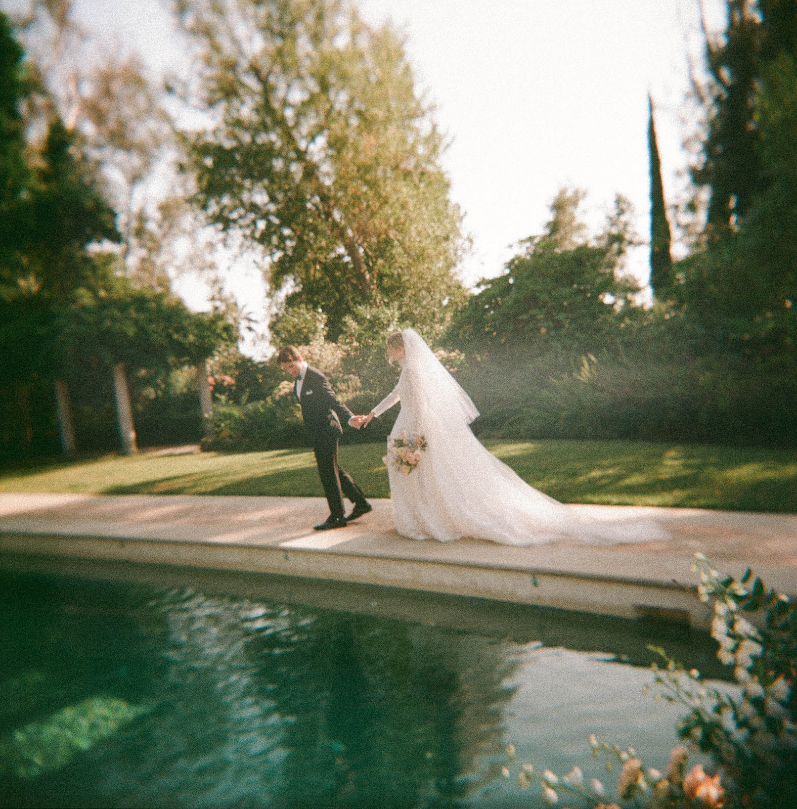 Pasadena bride and groom walking along poolside holding hands